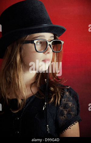 Mädchen im Zylinder gegen rot Stockfoto