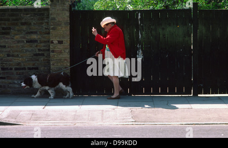 Ältere Dame mit Hut, die ihr Hund im Norden von London, 1983 Stockfoto