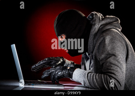 Hacker in einer Maske mit Laptop. Stockfoto