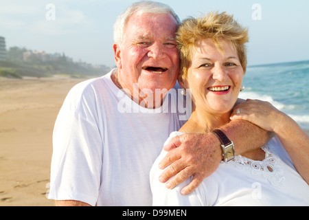 älteres paar umarmt am Strand lachen Stockfoto