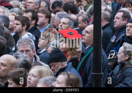 Menge am Ehrenmal in Whitehall, London am Remembrance Day Sonntag mit einer Frau einen Hut unverwechselbaren roten Mohn Stockfoto