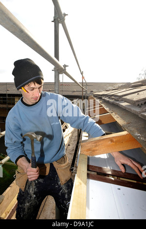 Dachdecker bei der Arbeit, die Reparatur eines undichten Daches auf einem Grundstück an einem sonnigen Tag in Cardiff, Südwales. Stockfoto