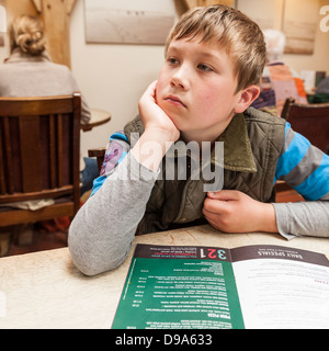 Ein 9-jähriger Junge schaut das Menü im Byfords Café in Holt, Norfolk, England, Großbritannien, Uk Stockfoto