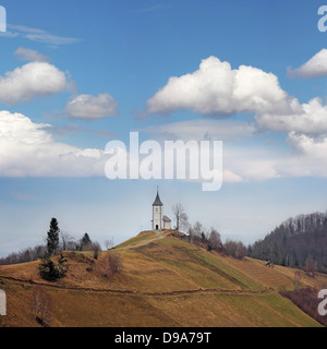 Kleine weiße Kirche auf einem oberen Hügel unter blauem Himmel Stockfoto