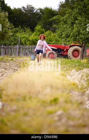 Bauer-Frau, die einen Eimer mit Dünger in einem Obstgarten, mit selektiven Fokus Stockfoto