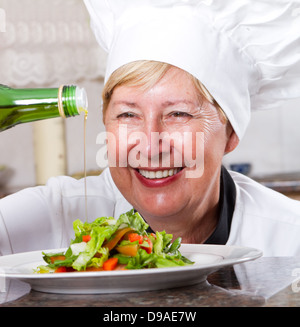 Senior Chef Dressing Salat mit Olivenöl Stockfoto