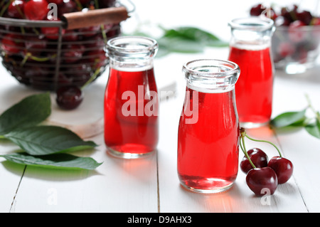 Kirschsaft in Gläsern und frische reife Kirschen auf hölzernen Hintergrund Stockfoto