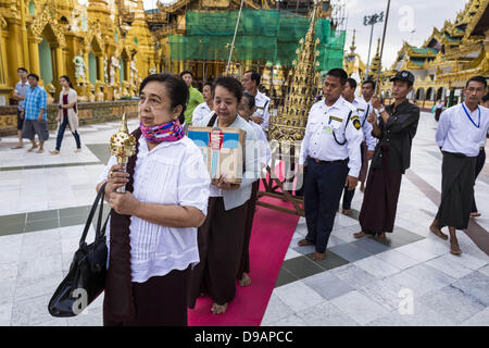 15. Juni 2013 - Yangon, Burma/Myanmar - führt eine Frau eine Familie Verdienst machen Prozession um Shwedagon-Pagode in Yangon. Die Shwedagon-Pagode ist offiziell bekannt als Shwedagon Zedi Daw und wird auch als der große Dagon Pagode oder die Goldene Pagode. Es ist 99 Meter (325Â ft) hohen Pagode und Stupa befindet sich in Yangon, Birma. Die Pagode liegt im Westen von auf Singuttara Hügel und dominiert die Skyline der Stadt. Es ist der heiligste buddhistische Pagode in Myanmar und enthält Relikte der Vergangenheit vier Buddhas verankert: die Mitarbeiter des Kakusandha, der Wasserfilter der Koá¹‡Ä Gamana, ein Stück von der Stockfoto