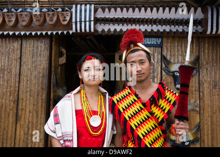 Naga Stammes paar in traditioneller Kleidung vor einer Hütte stehen Hornbill Festival, Kohima, Nagaland, Indien Stockfoto