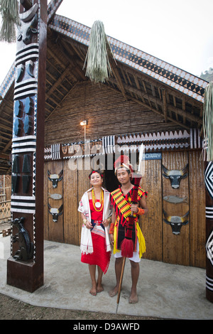 Naga Stammes paar in traditioneller Kleidung vor einer Hütte stehen Hornbill Festival, Kohima, Nagaland, Indien Stockfoto