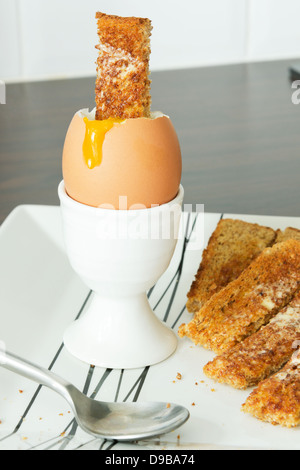 Laufende gekochtes Ei und Toast Soldaten Stockfoto