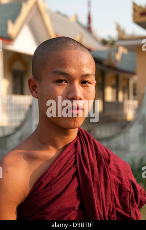 Teenager Mönch in roten Roben steht vor einem Tempel Myanmar-Burma Stockfoto