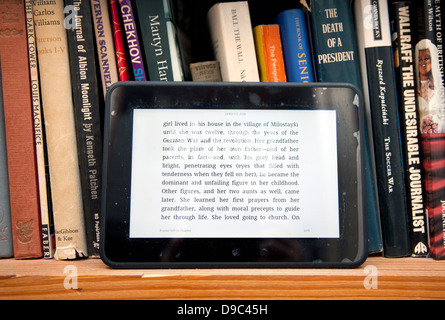 Kindle e-Book-Gerät und physische Bücher im Regal, London Stockfoto