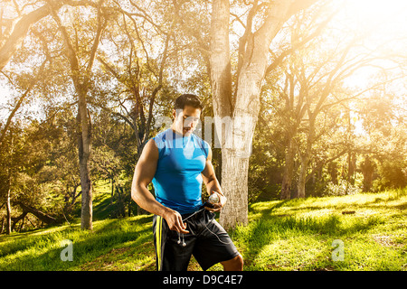 Junger Mann im Wald hält Ohrhörer Ausübung Stockfoto