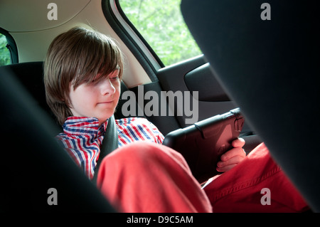 Kleiner männlicher Junge mit ipad Mini Tablet-Computer auf dem Rücksitz des Autos Stockfoto