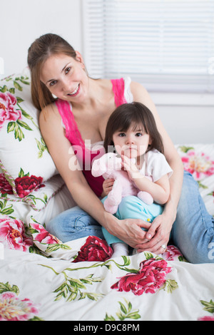Mutter und Kleinkind sitzen am Bett Stockfoto