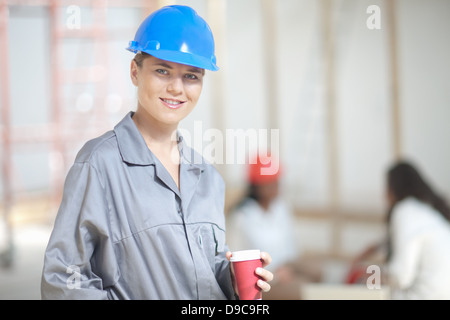 Lächelnde Frau Bauarbeiter mit Kaffee Stockfoto