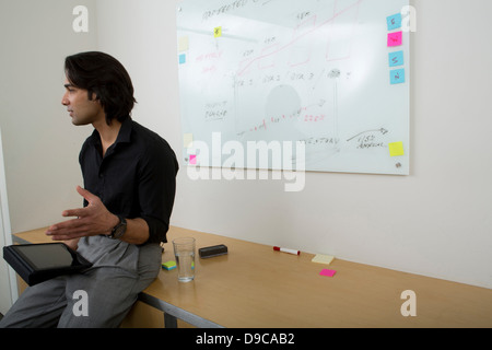 Junger Mann mit Whiteboard im Hintergrund Stockfoto