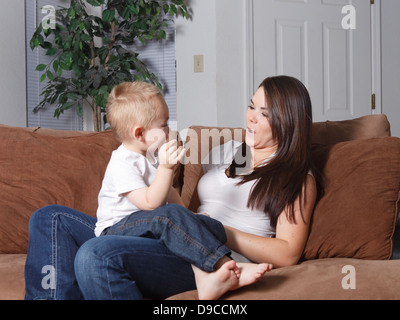 Mutter und junge Sohn sitzen auf der Couch zusammen zu Hause inmitten der Lebensstil beiläufig spielen zusammen Liebe und Bindung Stockfoto