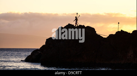 Klippenspringer trägt Fackel auf Black Rock am Kaanapali Beach, Maui bei Sonnenuntergang Stockfoto