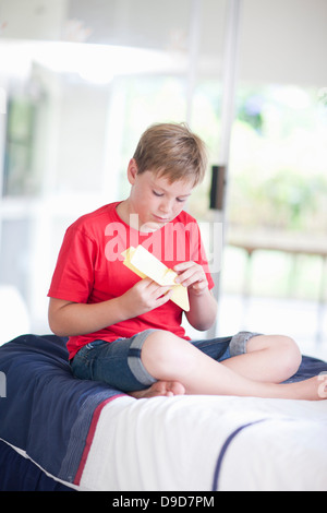 Junge im Bett spielen mit Papier Flugzeug Stockfoto