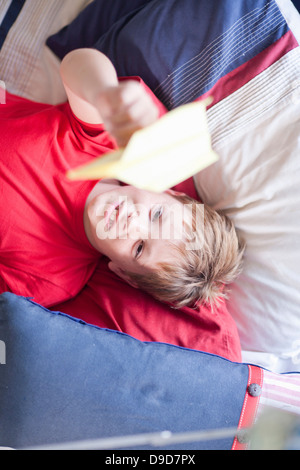 Junge im Bett spielen mit Papier Flugzeug Stockfoto