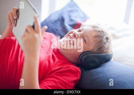 Junge auf Bett, Musik hören und mit digital-Tablette Stockfoto