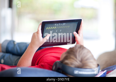 Junge auf Bett, Musik hören und mit digital-Tablette Stockfoto