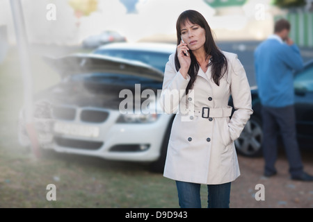 Frau auf dem Handy nach Autounfall Stockfoto