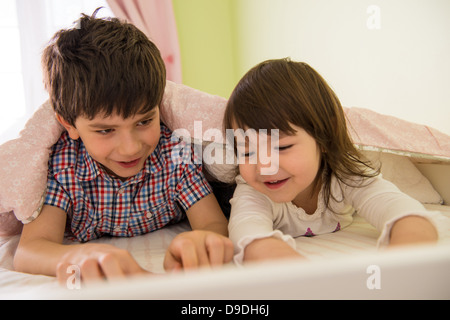 Bruder und Schwester auf Bett liegend Stockfoto