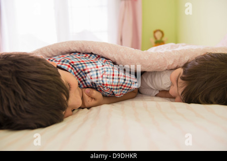 Bruder und Schwester auf Bett liegend Stockfoto