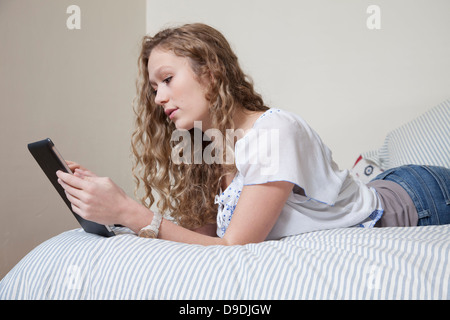 Teenager auf Bett, digitale Tablet lesen Stockfoto