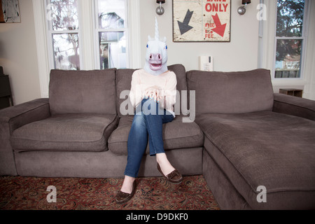 Mädchen sitzen auf dem Sofa mit Einhorn Kopf Maske Stockfoto