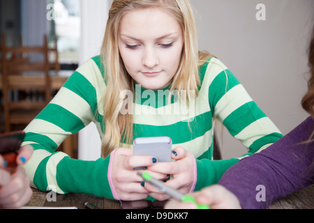 Mädchen am Tisch mit Smartphone Stockfoto