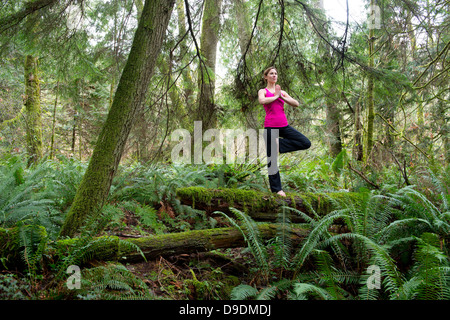 Reife Frau, die Durchführung von Baumpose im Wald Stockfoto