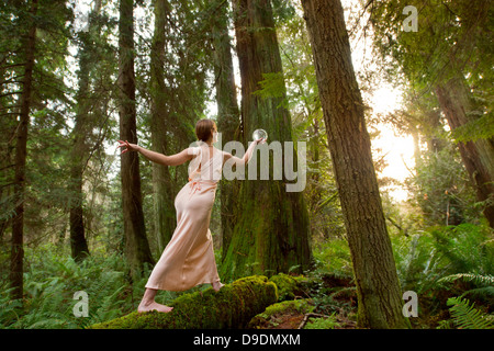 Reife Frau steht auf Log in Wald Stockfoto