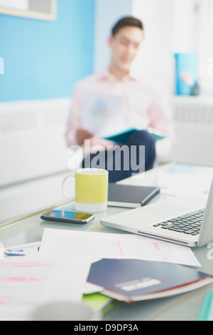 Laptop am Schreibtisch mit Mann im Hintergrund Stockfoto