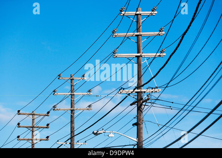 Kabel angeschlossen um telegraph Pole gegen blauen Himmel Stockfoto