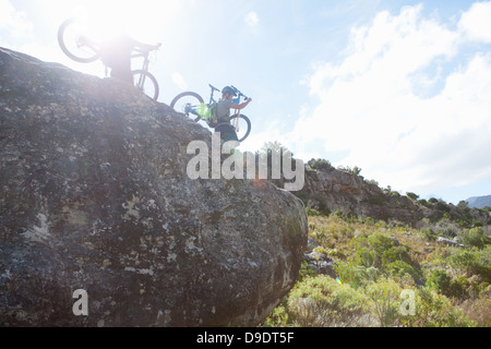 Junges Paar mit Mountain-Bikes nach unten vom Felsen Stockfoto