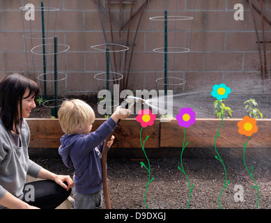 Mutter und Sohn mit Gartenschlauch im Garten Stockfoto