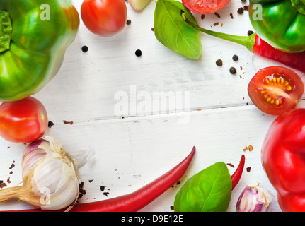 Pflanzliche Rahmen auf der hölzernen Tafel (rot und grün bell Paprika, Chilischoten, Knoblauch, Tomaten, Basilikum, Pfeffer) Stockfoto