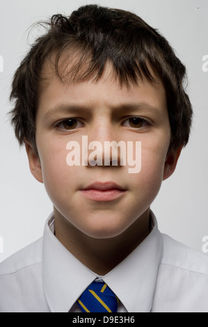 Ein junger Junge, der neugierig, reflektierend und aufmerksam ist, sieben oder acht Jahre alt, und direkt in das Lens Studio schaut Stockfoto