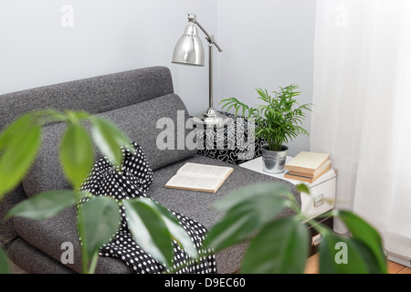 Gemütlicher Platz zum Lesen in einem Wohnzimmer, mit Pflanzen dekoriert. Stockfoto