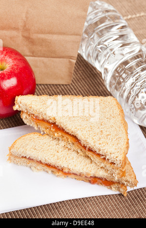 Erdnussbutter und Gelee Lunchpaket mit Wasser und Apfel Stockfoto