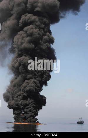 Dunkle Wolken von Rauch und Feuer entstehen, wie bei einem kontrollierten Brand in den Golf von Mexiko Öl verbrennt. Stockfoto