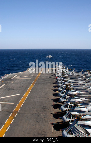 Ein AV-8 b zieht aus dem Flugdeck der USS Tarawa gesäumt von Hubschraubern. Stockfoto