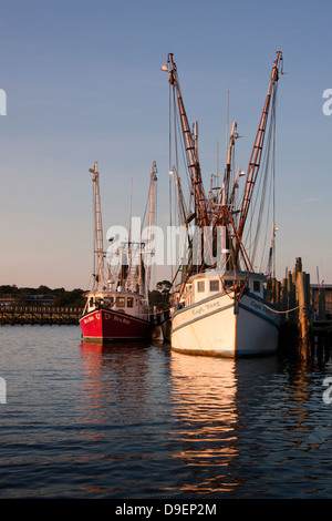 Die Sonne geht auf der aktiven Uferpromenade entlang Shem Creek, Mount Pleasant, South Carolina, USA in ein warmes Licht baden. Stockfoto