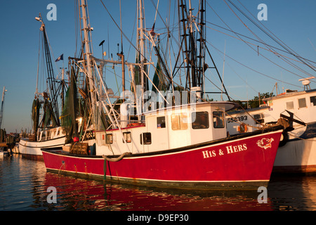 Die Sonne geht auf der aktiven Uferpromenade entlang Shem Creek, Mount Pleasant, South Carolina, USA in ein warmes Licht baden. Stockfoto