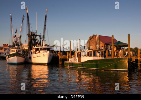 Die Sonne geht auf der aktiven Uferpromenade entlang Shem Creek, Mount Pleasant, South Carolina, USA in ein warmes Licht baden. Stockfoto