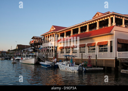 Die Sonne geht auf der aktiven Uferpromenade entlang Shem Creek, Mount Pleasant, South Carolina, USA in ein warmes Licht baden. Stockfoto